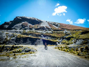 Person riding umbrella on mountain road against sky