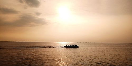 Silhouette boat sailing in sea against sky during sunset