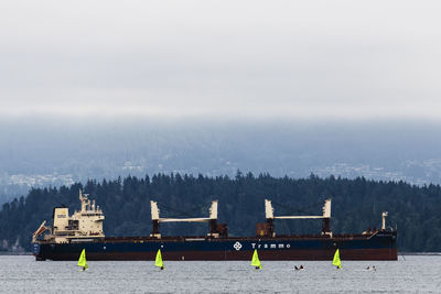 Boats moored at harbor against sky during winter