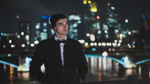 Portrait of young man standing in city at night