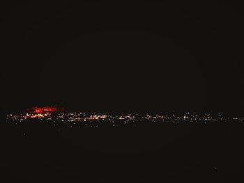 Illuminated cityscape against sky at night