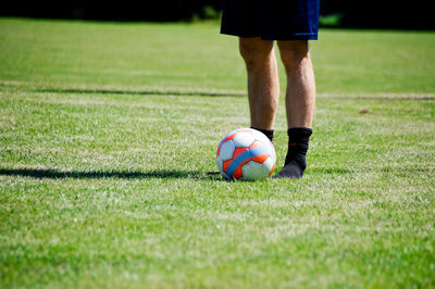 Low section of man playing soccer on grass