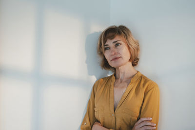 Mature woman with blond hair standing in front of wall