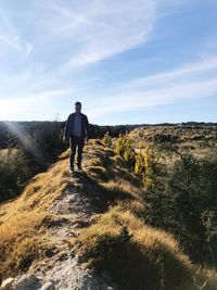 Rear view of man walking on mountain against sky