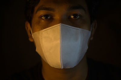 Close-up portrait of man covering face against black background