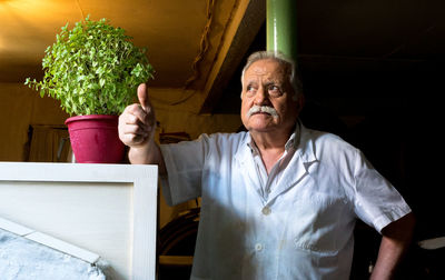 Senior man standing by potted plant