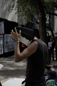 Side view of man covering face while standing in city