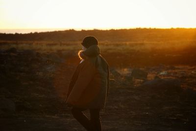 Woman walking on field during sunset