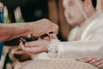 Cropped hand of woman making wedding dress. the wrist tie is a thai marriage.