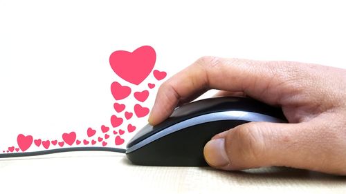 Close-up of hand using mouse on table against white background