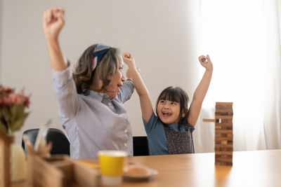 Cheerful mother and daughter playing jenga at home