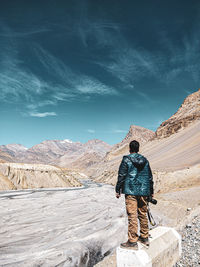 Rear view of man standing on mountain against sky