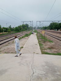 Rear view of man walking on railroad track