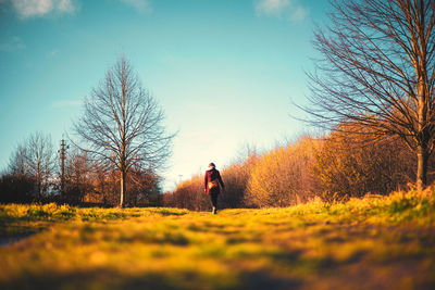 Rear view of woman standing on field against sky