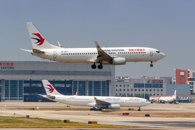 Airplane flying over airport runway against sky