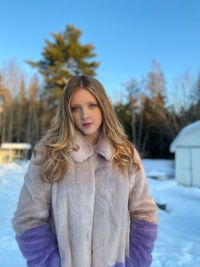 Portrait of cute teenage girl standing against trees during winter