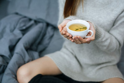 Midsection of woman holding coffee at home