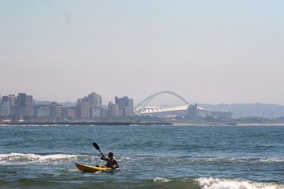 Man kayaking in sea against clear sky