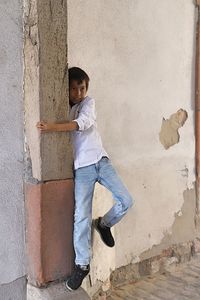 Side view of boy standing against wall