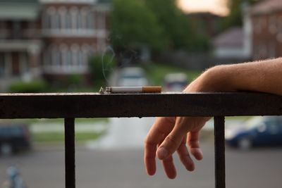 Close-up of hand holding cigarette against blurred background