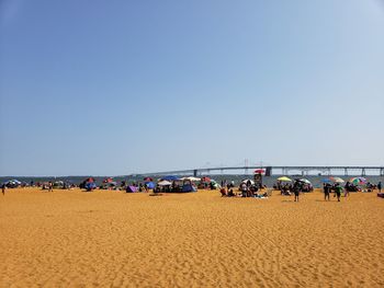 People on beach against clear sky