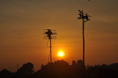 Low angle view of silhouette telephone pole against sky during sunrise