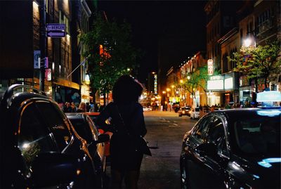 Rear view of woman standing on city street at night