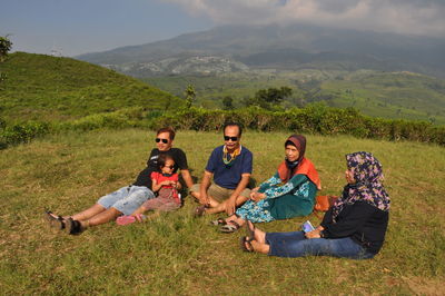 Group of people relaxing on mountain against sky