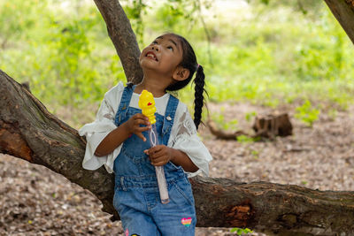 Girl looking up while standing on tree trunk
