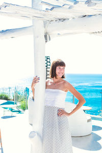 Portrait of woman standing by swimming pool against sky