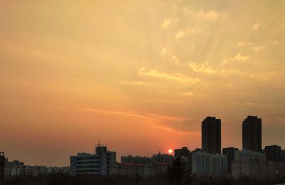 Modern cityscape against sky during sunset