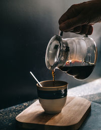 Cropped image of hand pouring coffee cup on table