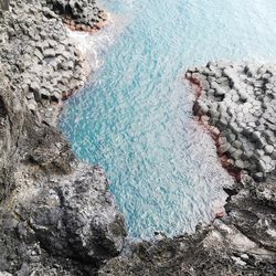 High angle view of volcanic rocks in sea