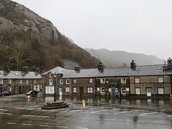 Buildings by road against sky during rainy season