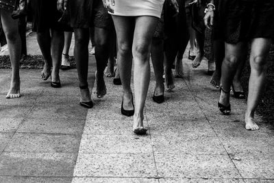 Low section of people walking on street in city