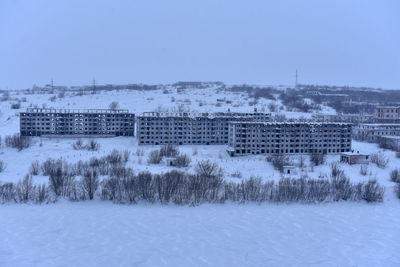 Snow covered trees and buildings against sky