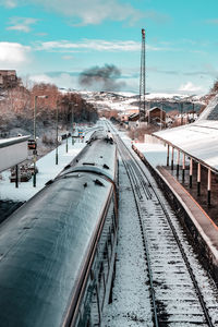 Snow covered railroad tracks against sky during winter