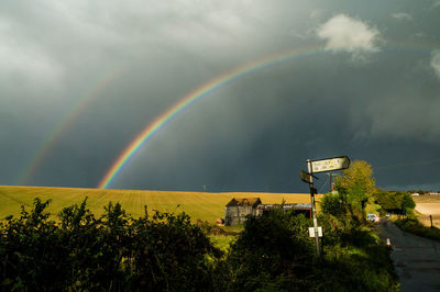 Scenic view of rainbow over trees against sky