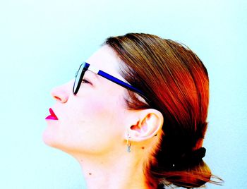 Close-up of woman wearing eyeglasses against blue background