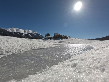 Scenic view of snowcapped mountains against clear sky during sunny day