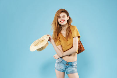 Portrait of smiling young woman against blue background