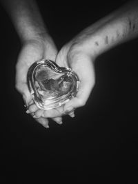 Close-up of hand holding glass over black background