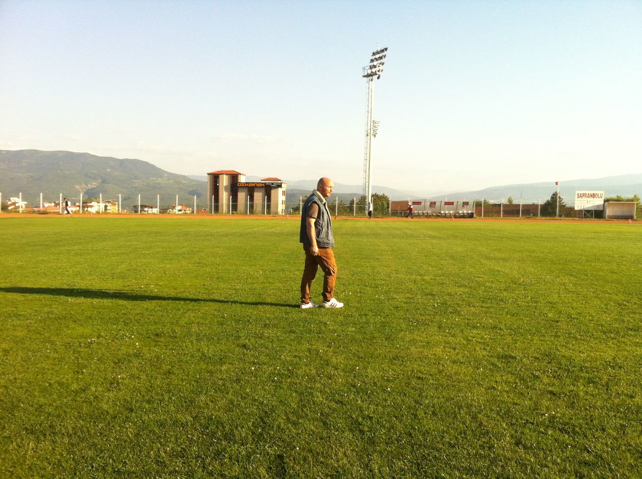 full length, lifestyles, grass, leisure activity, casual clothing, clear sky, field, standing, men, grassy, green color, landscape, rear view, walking, copy space, sport, day, sky