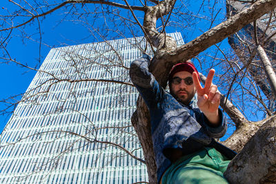 Low angle portrait of man against bare tree