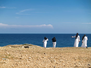 Rear view of nuns standing on cliff in front of sea
