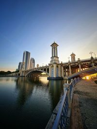 View of buildings by river in city against clear sky