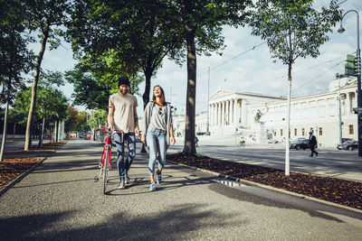 Austria, vienna, young couple with bicycle in front of parliament building