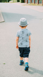 A little boy in a hat and shorts walks on the street on a fine summer day