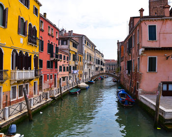 Canal amidst buildings in city against sky