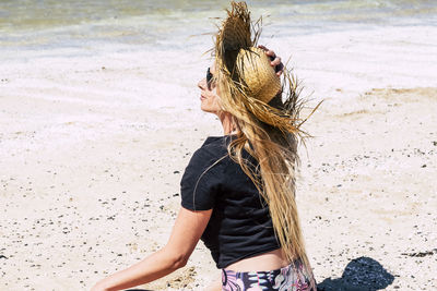 Woman wearing hat while sitting at beach